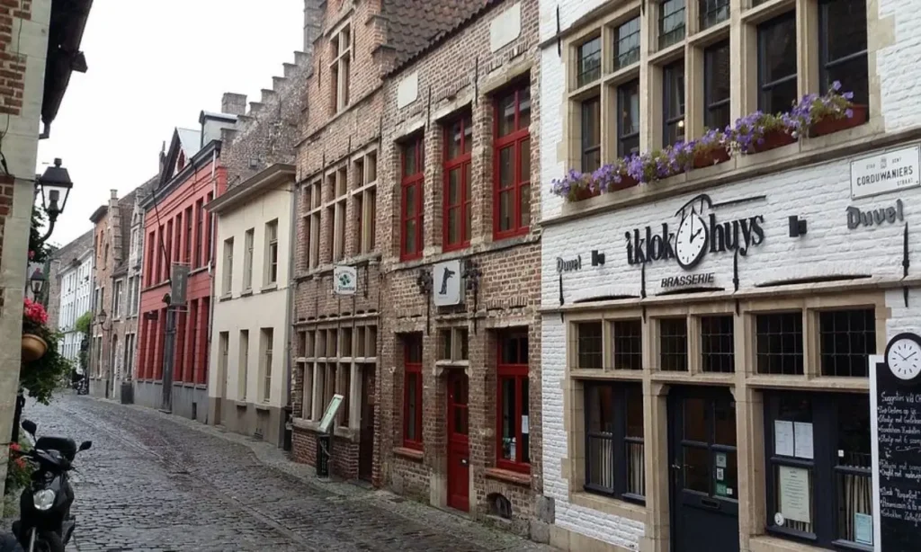 A narrow cobblestone street in Patershol lined with historic brick buildings and cafés.