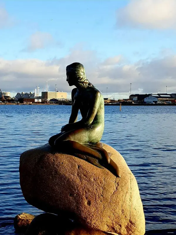 The Little Mermaid statue sitting on a rock by the water in Copenhagen.