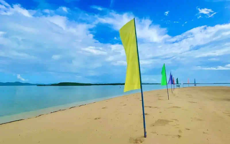 Sandy beach with colorful flags along the shore at Honda Bay.