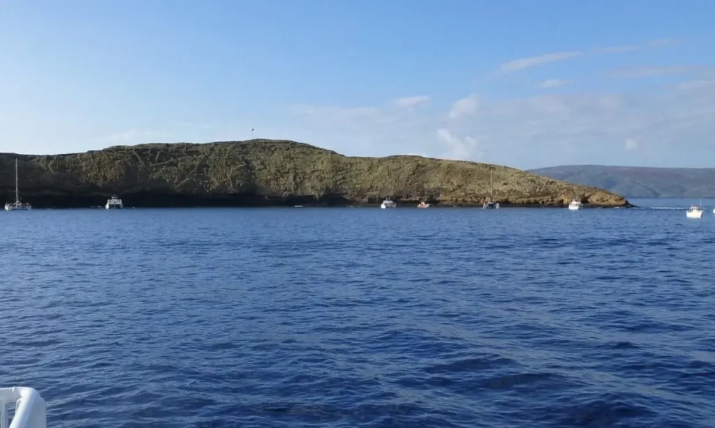 Boats anchored near the crescent-shaped Molokini Crater in the ocean.
