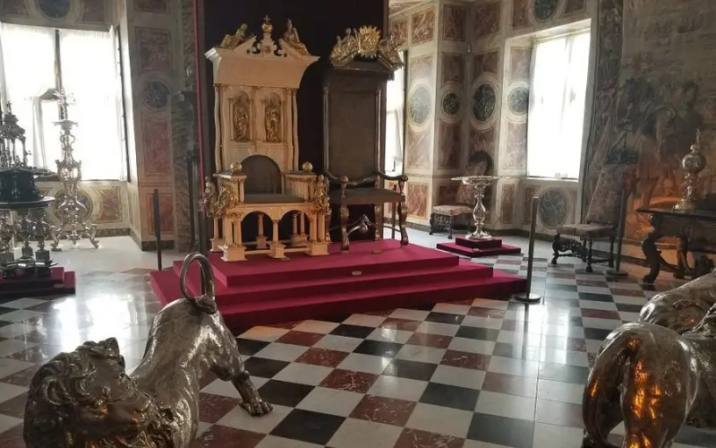 The throne room with ornate chairs and silver lions inside Rosenborg Castle.