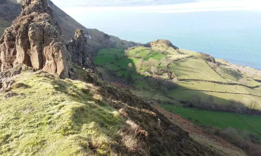 The Nine Glens of Antrim display rocky hills and green fields overlooking the sea.