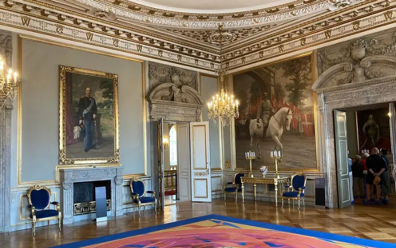 Ornate interior room with paintings and chandeliers in Christiansborg Palace.