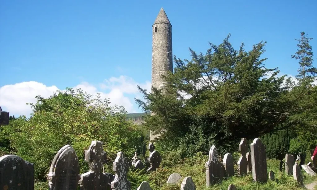 Glendalough features a tall round tower surrounded by old gravestones and greenery.