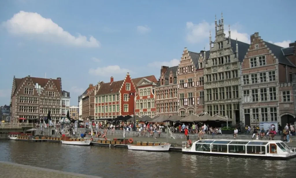 Graslei and Korenlei canal lined with historic buildings, boats, and people on a sunny day.