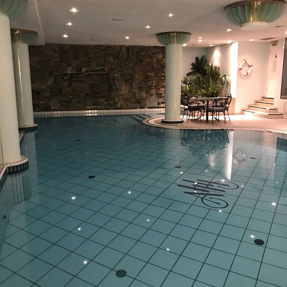 Indoor pool area at Aghadoe Heights Hotel & Spa with seating and stone wall feature.