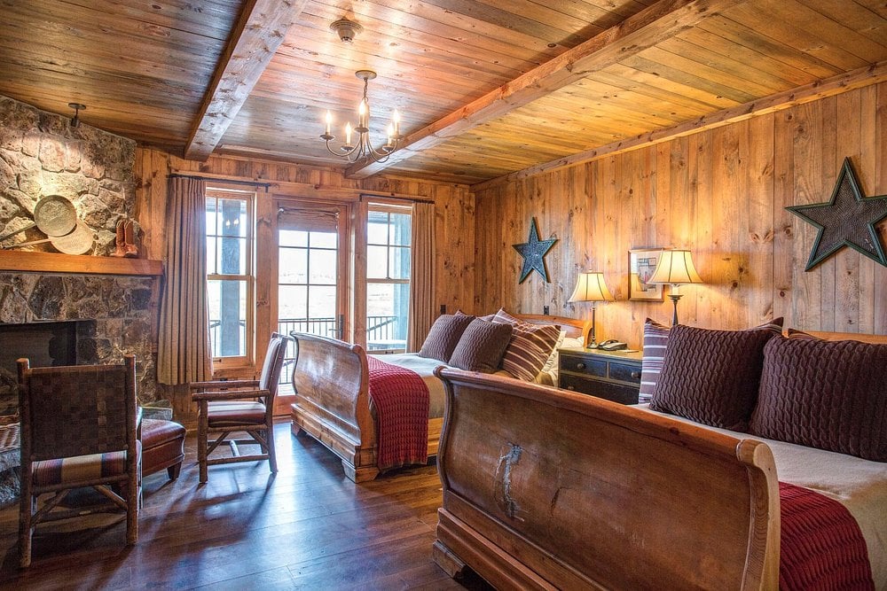 Rustic wood-paneled guest room at Devil's Thumb Ranch Resort & Spa with fireplace and double beds.