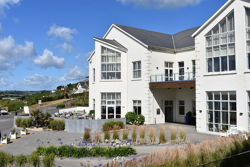Inchydoney Island Lodge & Spa with white facade and coastal views under a blue sky.