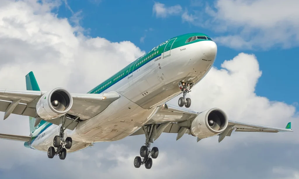 An underbelly view of an Aer Lingus Airbus A330 passenger airplane flying overhead