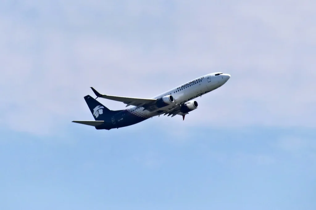 Aeroméxico Boeing 737 MAX commercial airplane ascending into a hazy blue sky after takeoff