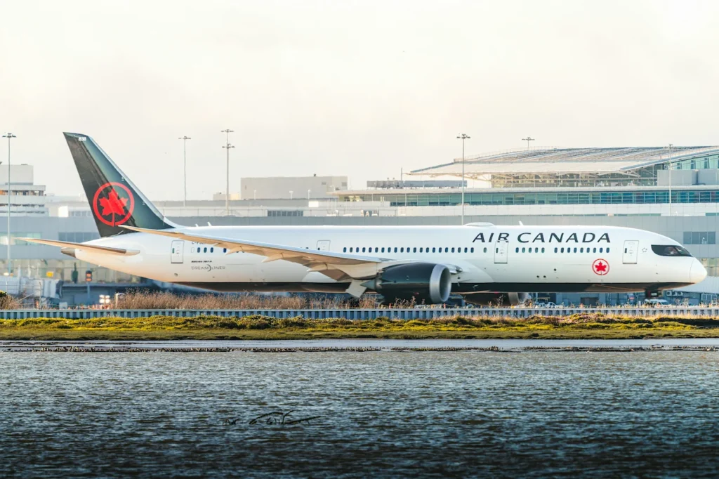 Air Canada Boeing 787 Dreamliner widebody commercial airplane taxiing on an airport runway near a body of water