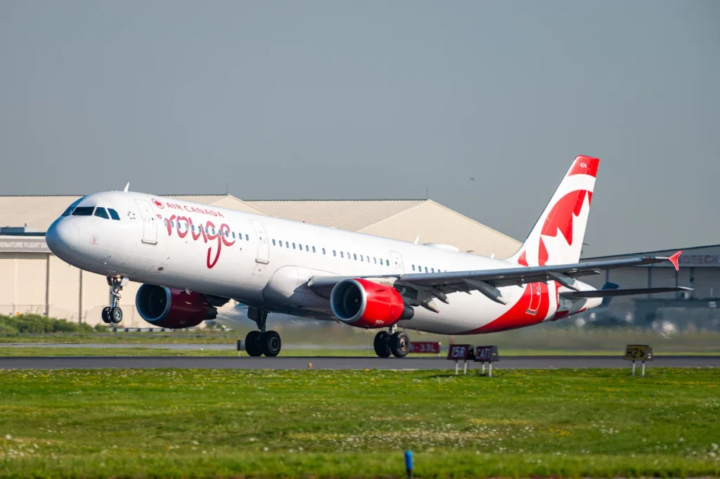 Air Canada Rouge Airbus A321 passenger airplane tilting upward during takeoff from an airport runway
