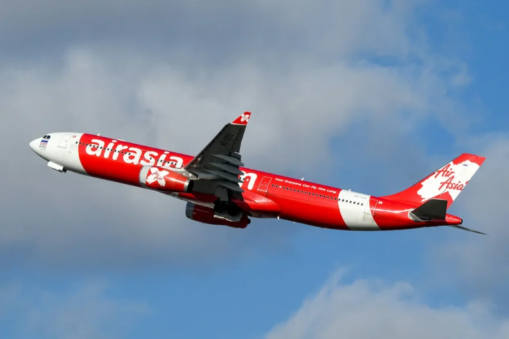 AirAsia X Airbus A330 widebody aircraft climbing into a partly cloudy blue sky after takeoff