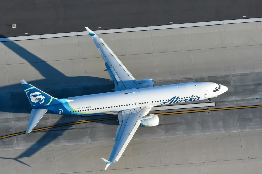 An overhead, top-down view of a white and blue Alaska Airlines Boeing 737 passenger airplane