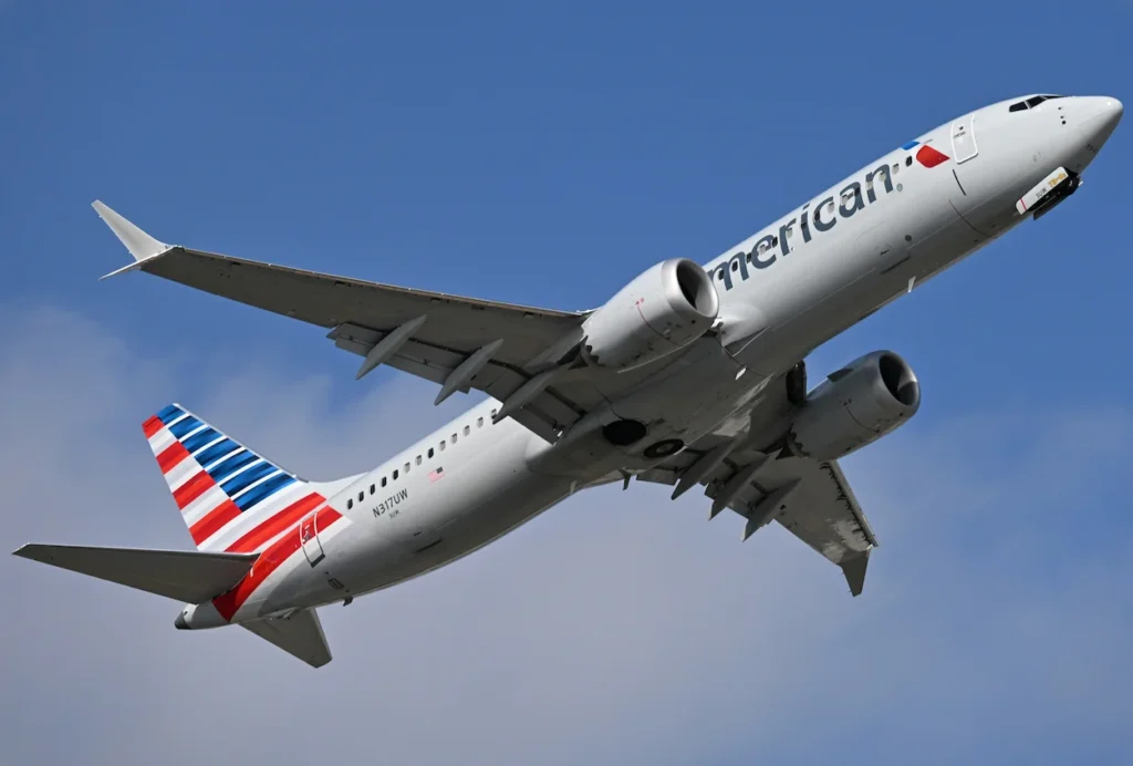 American Airlines Airbus A321 passenger airplane banking upward into a partly cloudy blue sky
