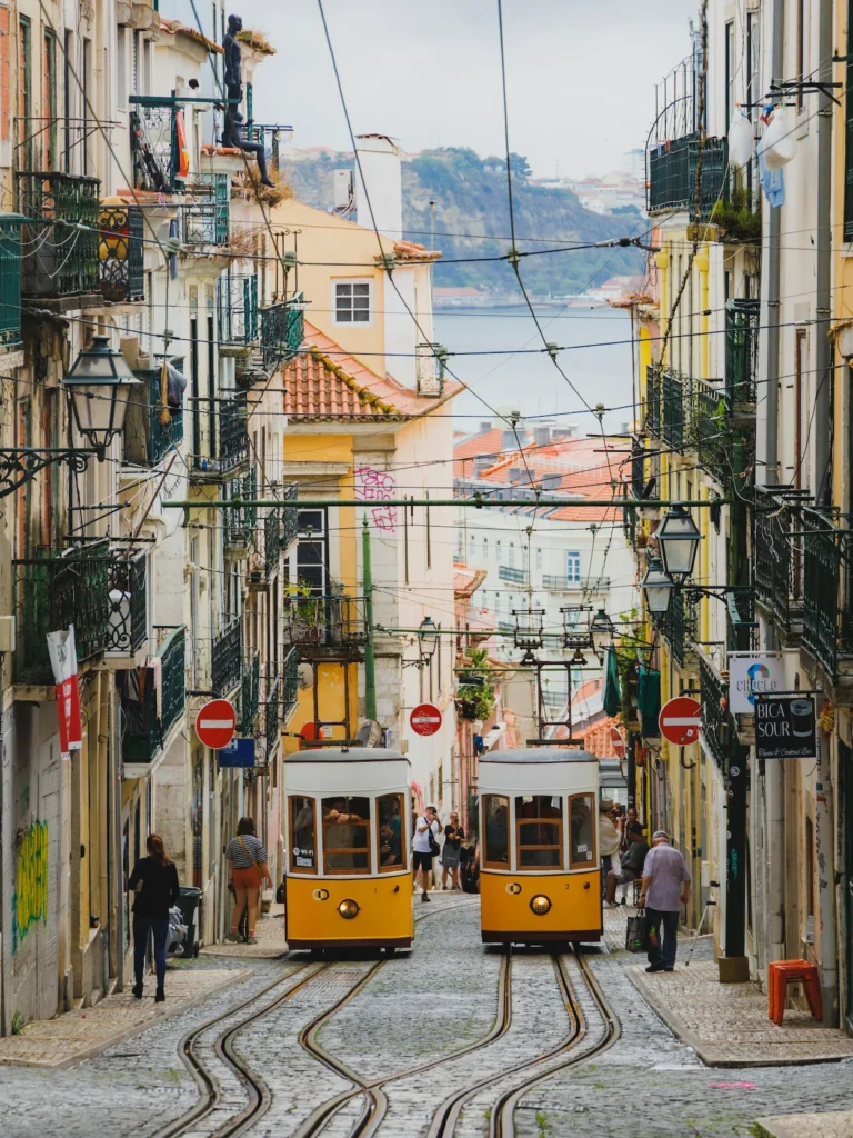 Two yellow Bica funicular trams on tracks on a steep narrow street in Lisbon
