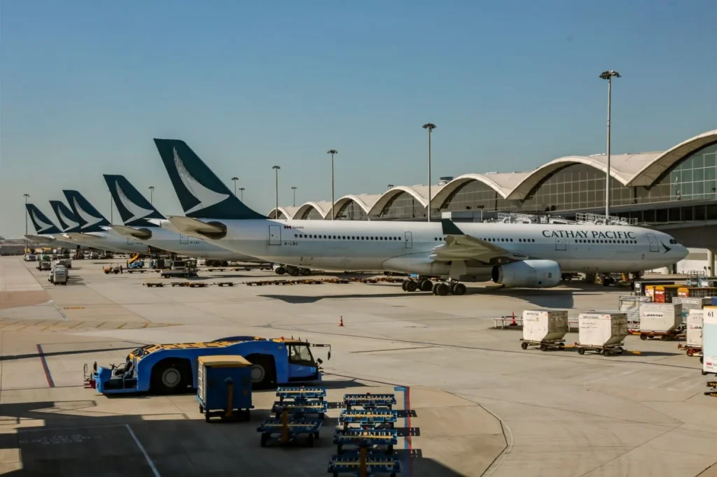 A row of Cathay Pacific passenger airplanes parked at airport terminal gates on the tarmac