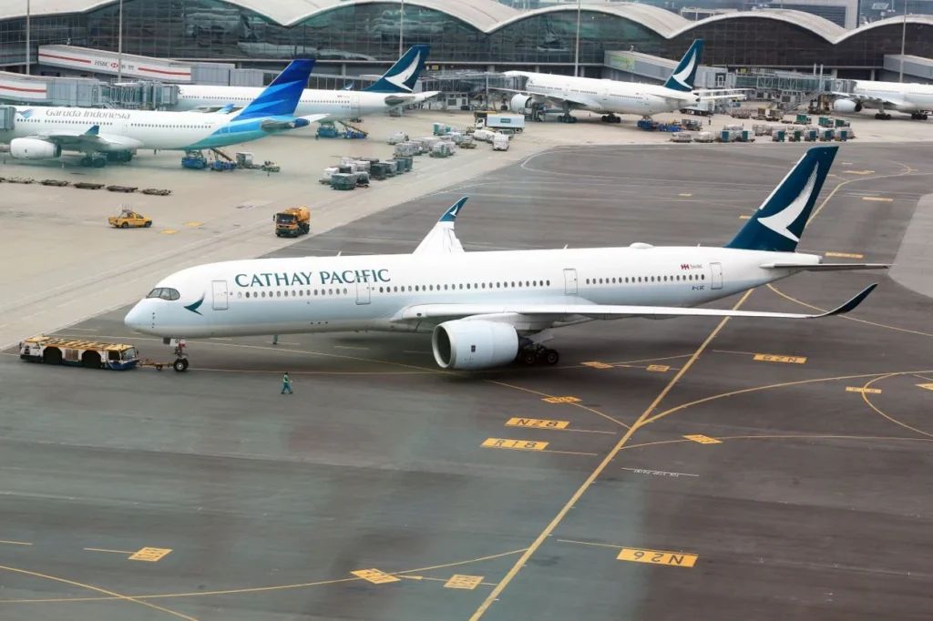 A Cathay Pacific Airbus A350-900 passenger airplane being pushed back by a tug vehicle