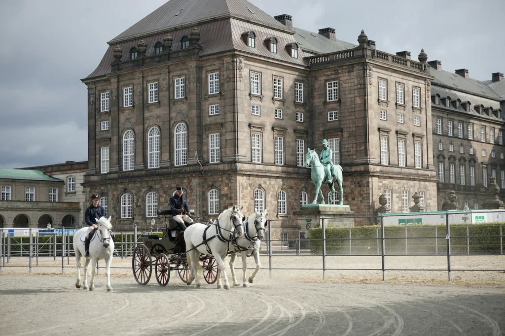 White horses pulling a carriage outside Christiansborg Palace in Copenhagen