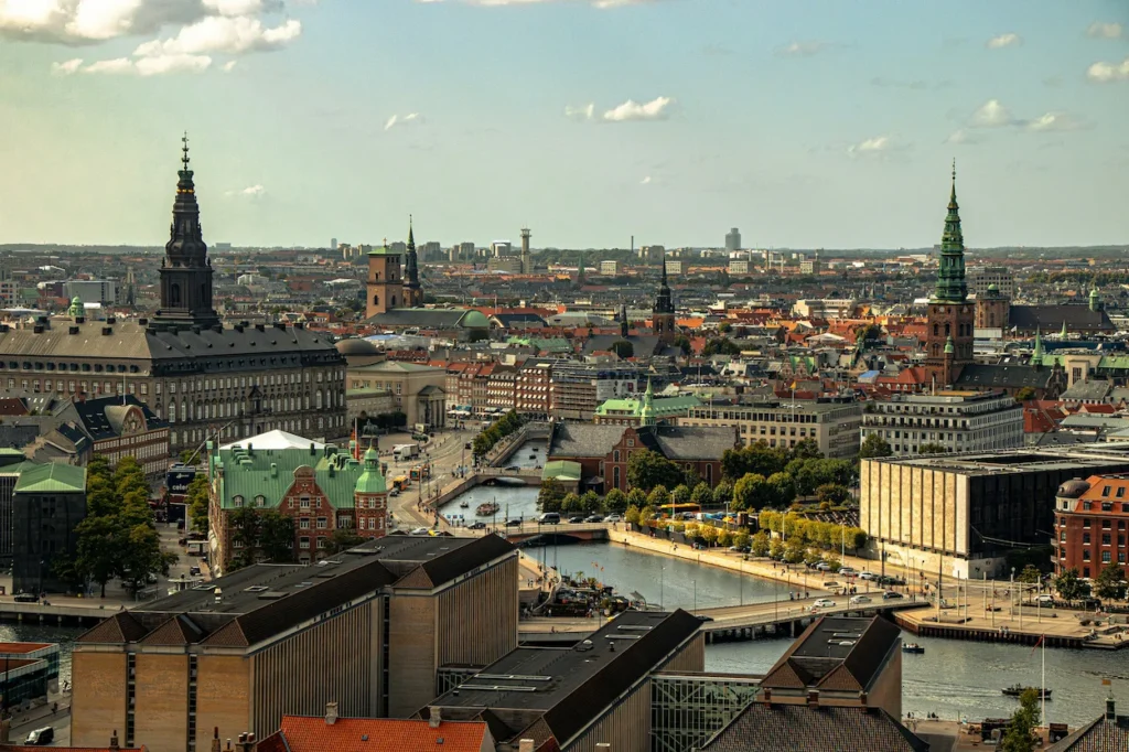 Aerial view of the Copenhagen skyline featuring historic spires, canals, and Christiansborg Palace