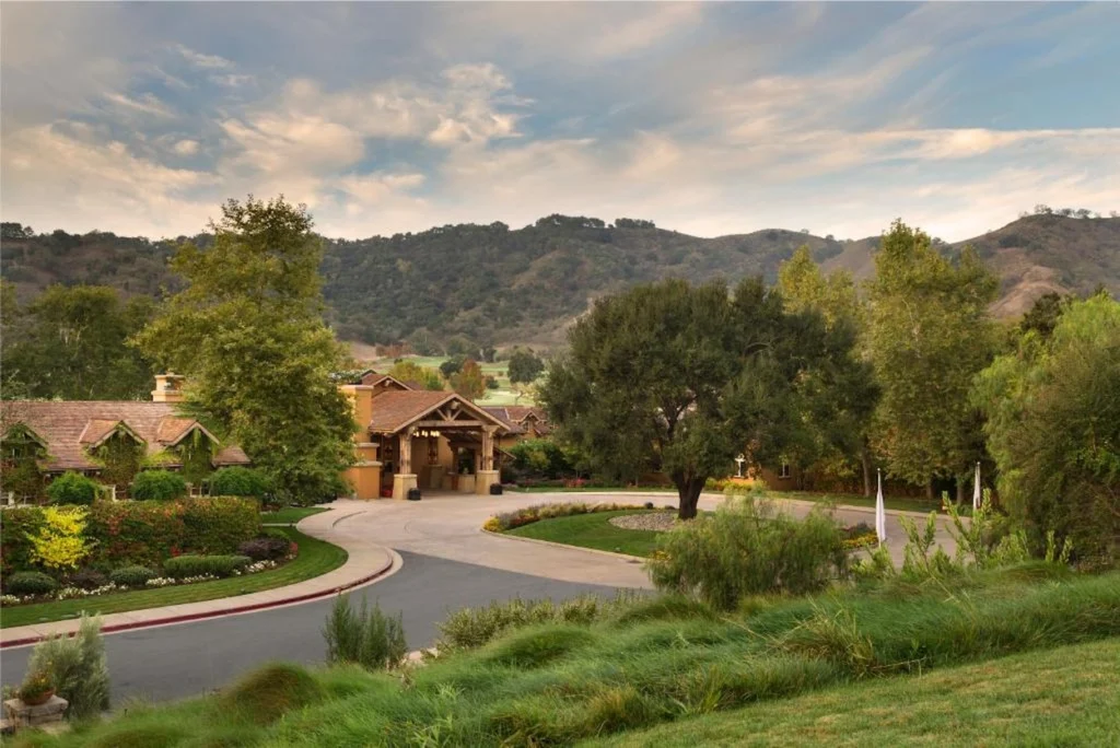CordeValle resort entrance in San Martin, California, showing a paved driveway, green lawns, and mountains