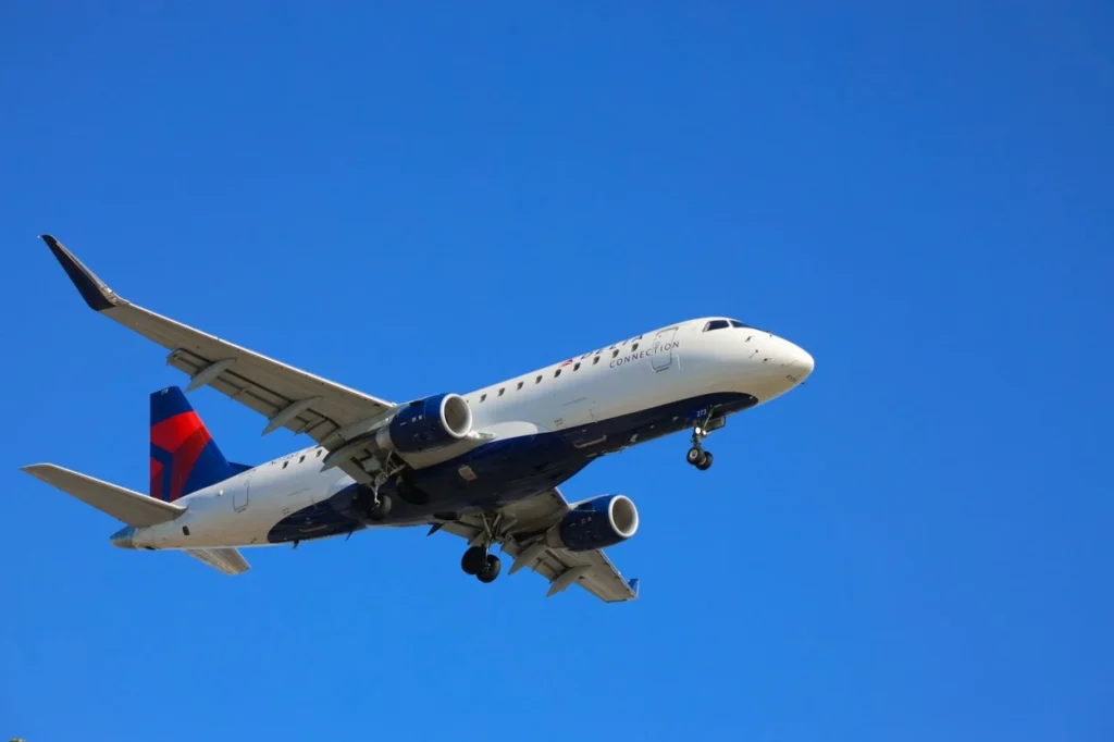 Delta Connection Embraer 175 regional jet flying in a clear blue sky