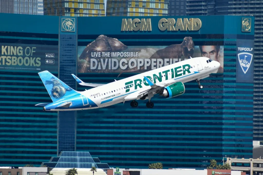 Frontier Airlines Airbus A320neo airplane taking off in front of the turquoise MGM Grand hotel