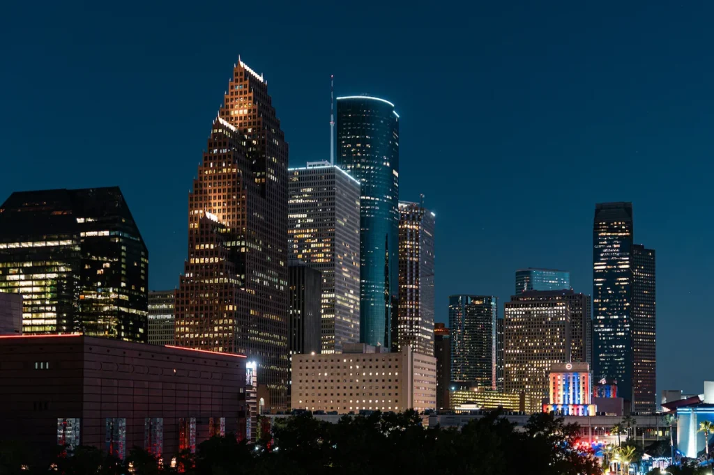 Downtown Houston skyline at night with illuminated skyscrapers against a dark blue sky
