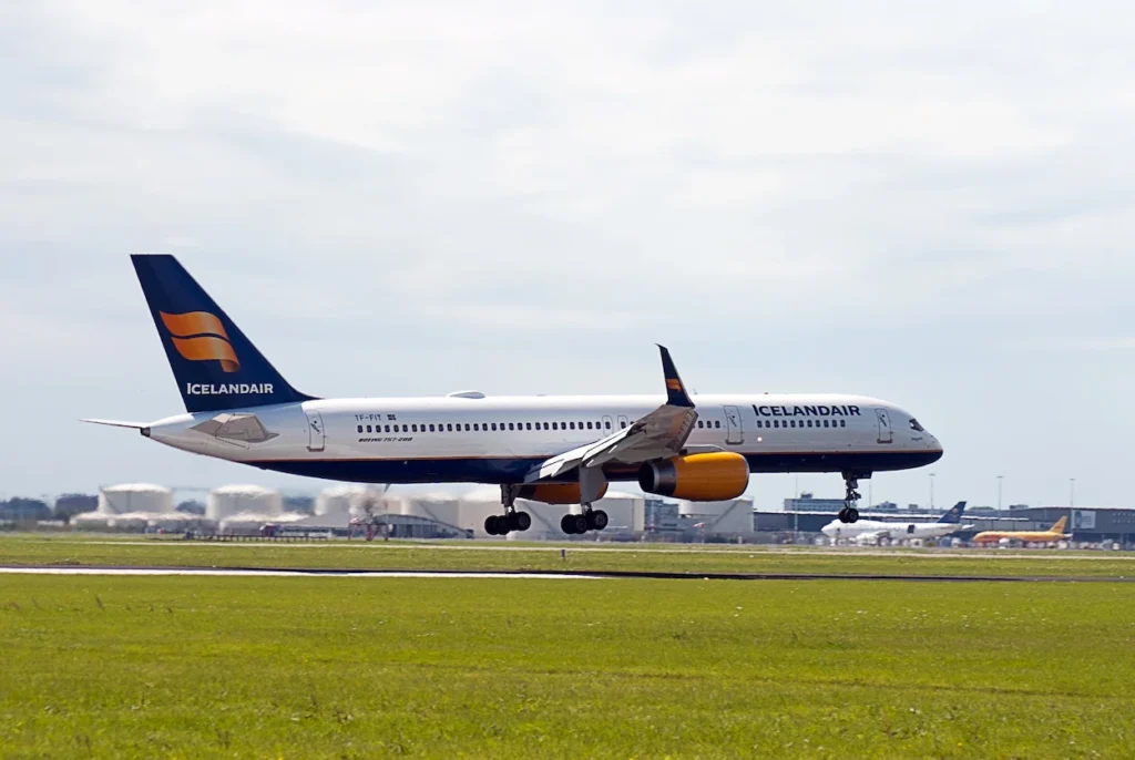 An Icelandair Boeing 757 passenger airplane with yellow engines landing on a runway