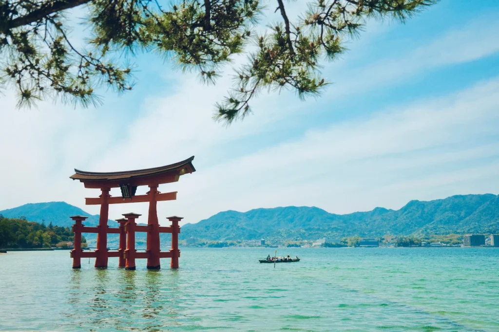 Red torii gate of Itsukushima Shrine standing in the sea with mountains behind