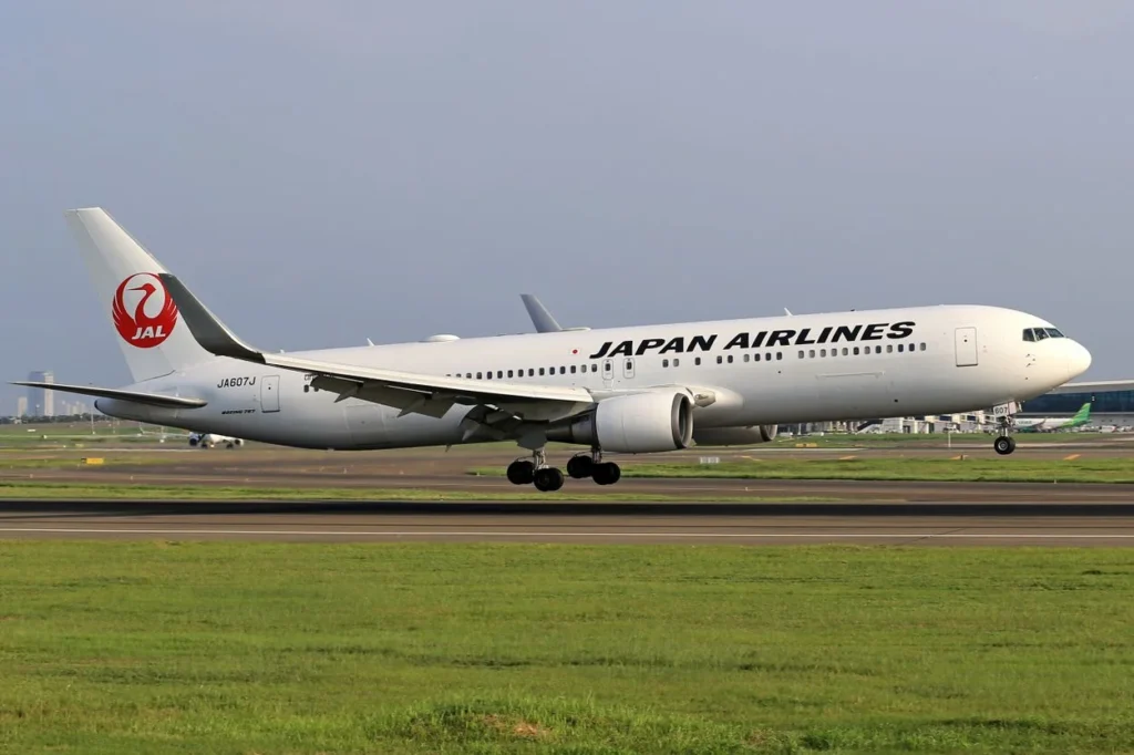 A white Japan Airlines Boeing 767-300ER airplane with the red crane logo