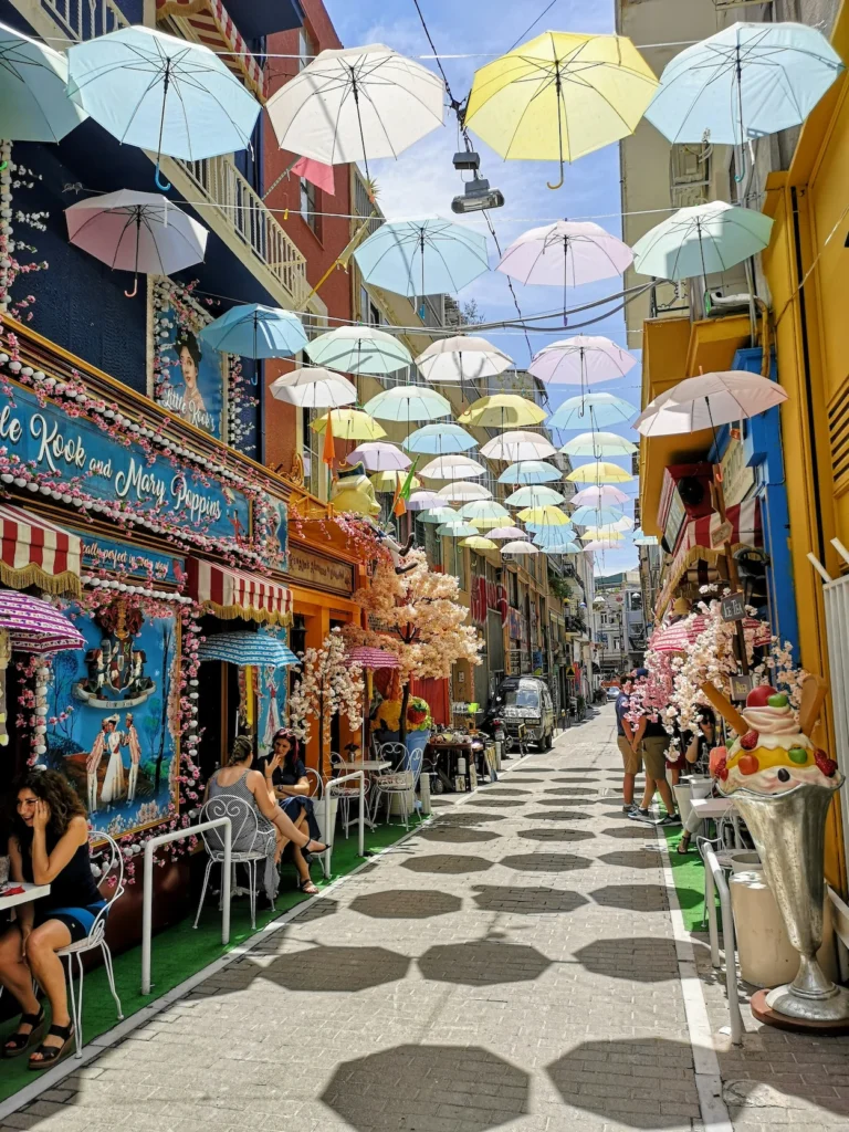 Colorful pastel umbrellas hanging overhead in a decorated Athens cafe street alley