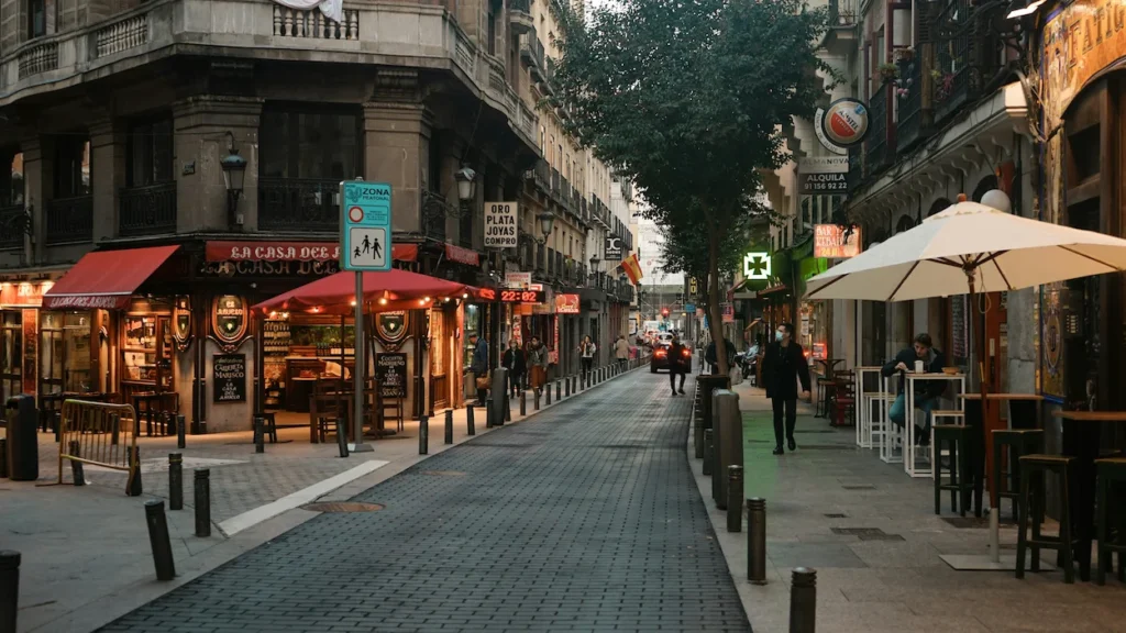Cobblestone street in Madrid at dusk featuring outdoor cafe seating and La Casa del Abuelo restaurant