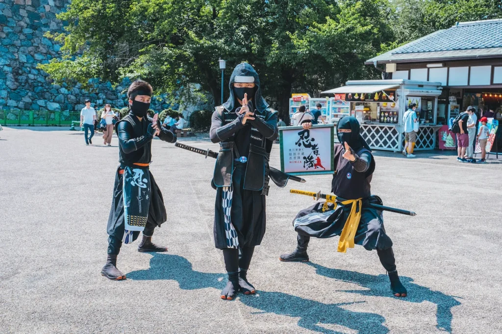 Three costumed ninjas striking dramatic martial arts poses outdoors