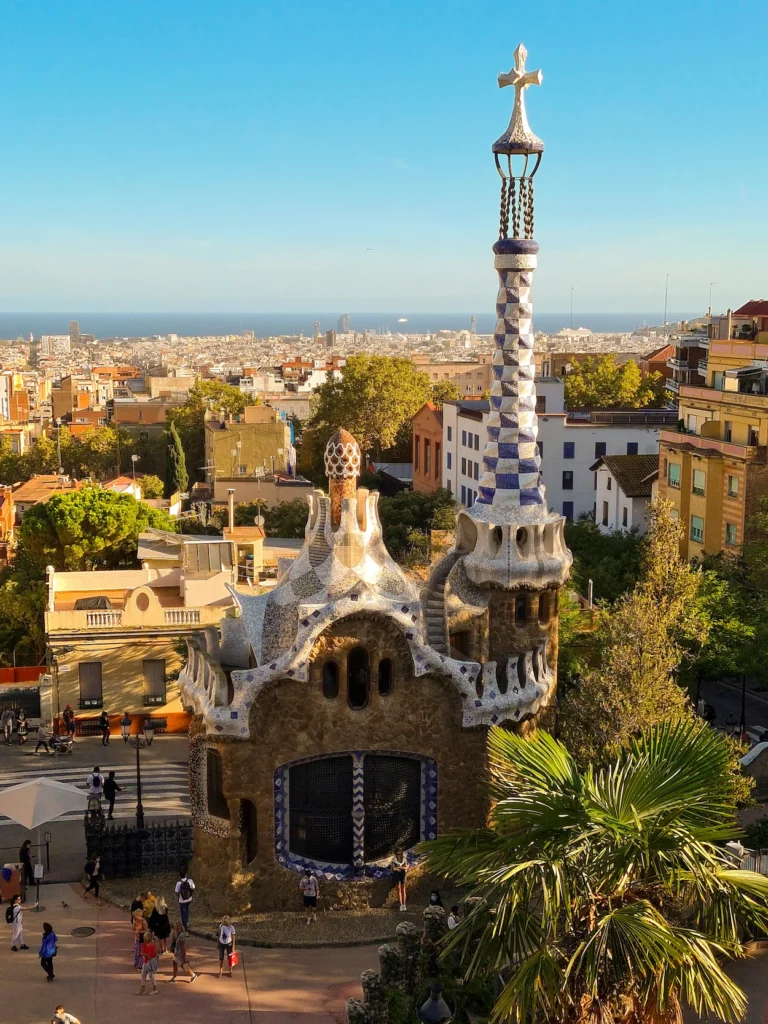 Park Güell gatehouse featuring a blue and white tiled spire overlooking the city of Barcelona