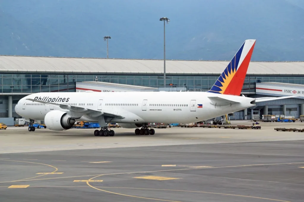 A Philippine Airlines Boeing 777 aircraft parked on an airport tarmac near a terminal