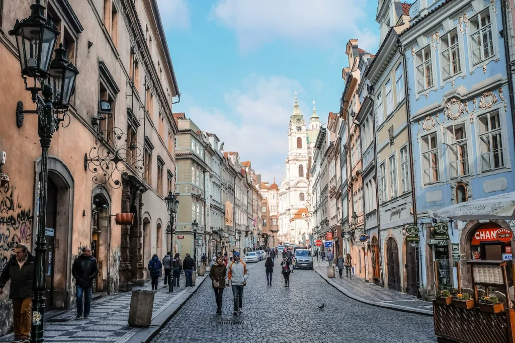Cobblestone street in Prague Old Town with historic buildings leading toward St. Nicholas Church