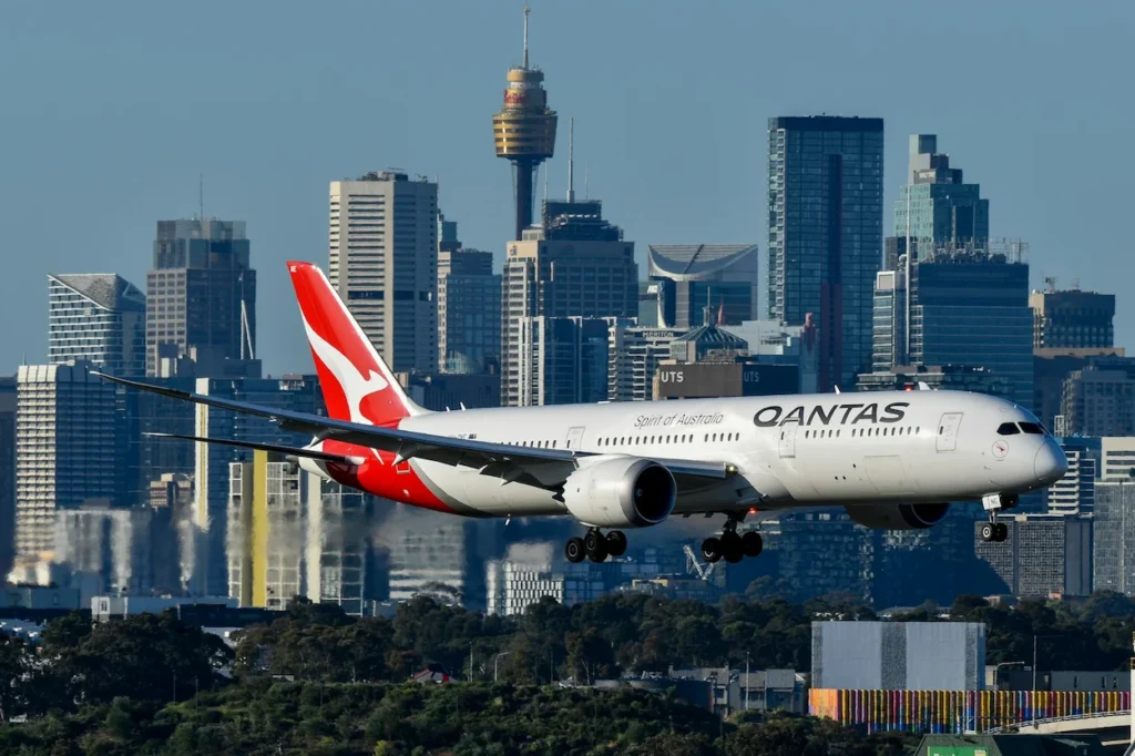 Qantas Boeing 787 airplane descending over Sydney with the city skyline behind it