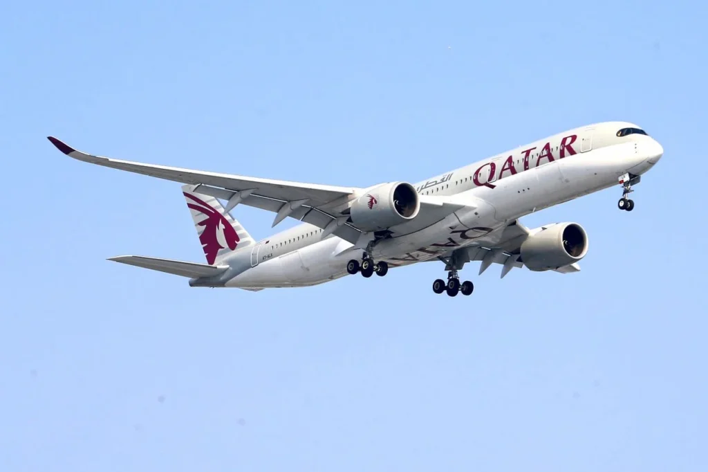 A Qatar Airways Airbus A350-1000 passenger airplane flying through a clear sky