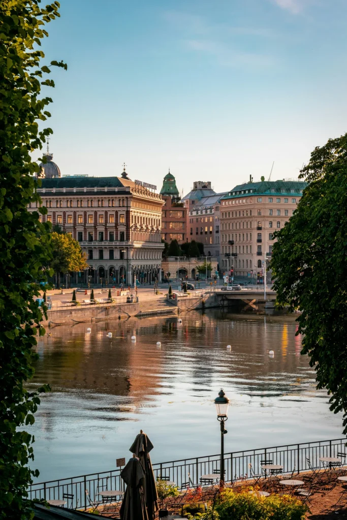 View of historic European buildings framing a calm urban river under a clear blue sky in Stockholm