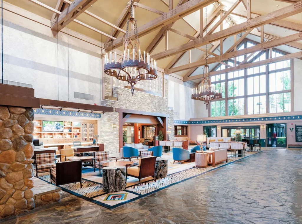 Spacious mountain resort lobby with a high vaulted wood ceiling, stone accents, and iron chandeliers
