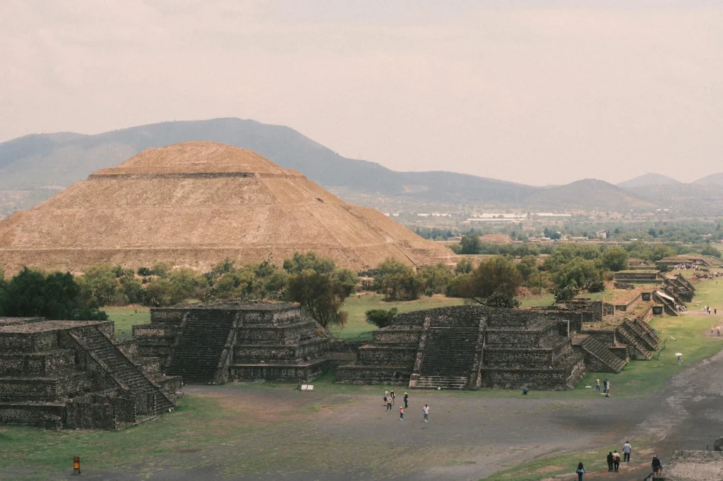 The ancient stone Pyramid of the Sun rising behind smaller stepped ruins at Teotihuacan in Mexico