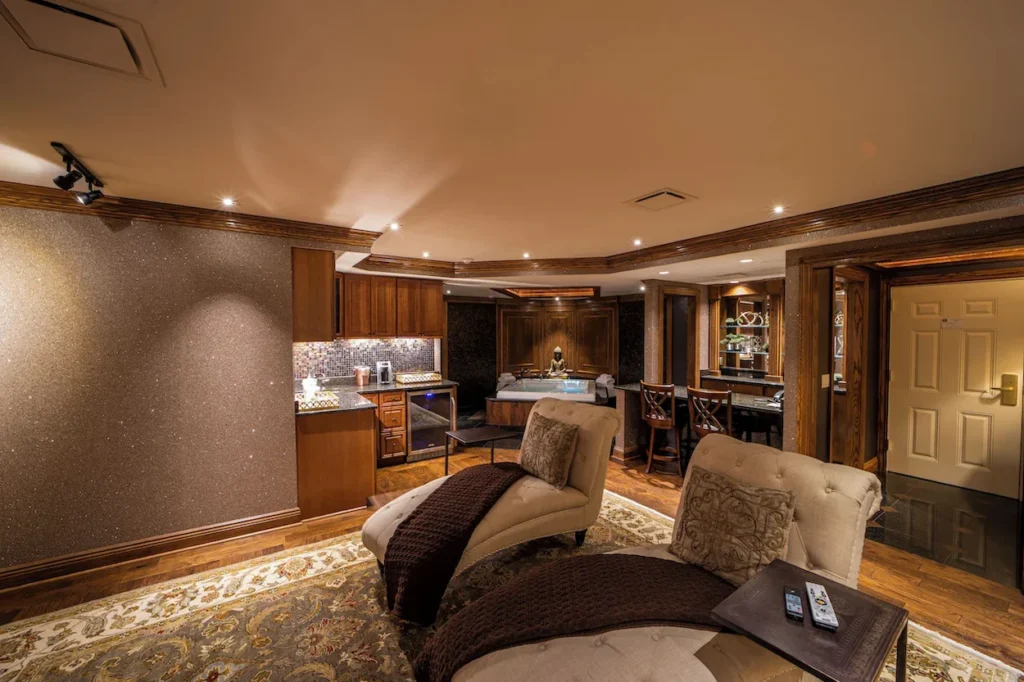 A resort spa suite with two tufted chaise lounges, a small kitchenette, and a hot tub