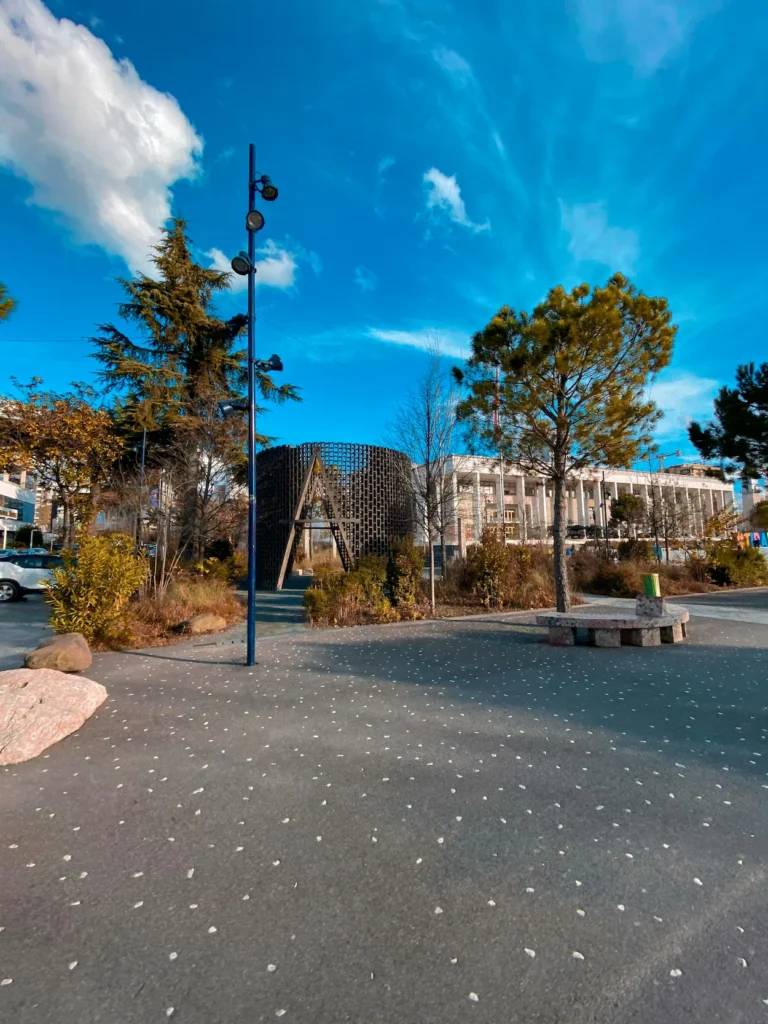 Europe Park in Tirana featuring a circular wooden lattice pavilion alongside trees and paved walking paths