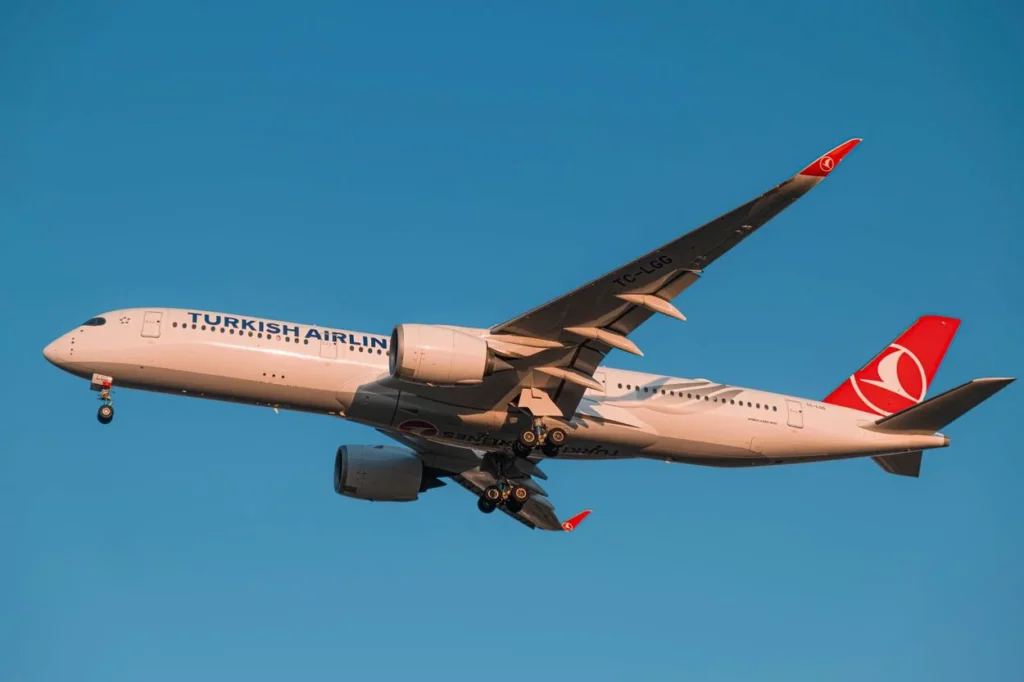 Turkish Airlines Airbus A350 passenger airplane flying through a deep blue sky with its landing gear down
