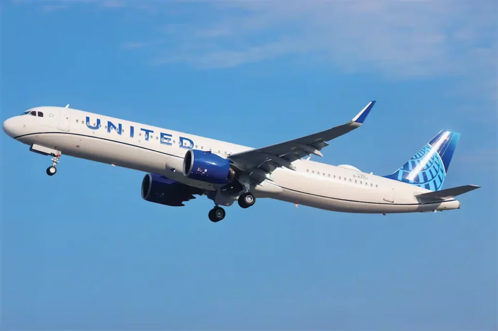 United Airlines Airbus A321neo passenger airplane climbing into a clear blue sky with its landing gear still extended