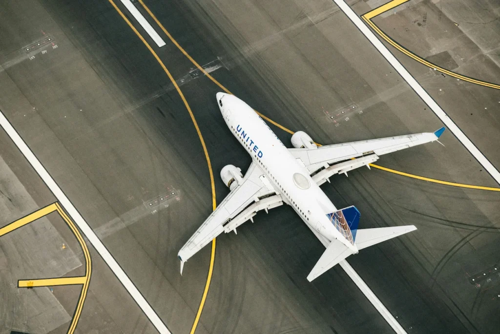 An overhead view of a blue and white United Airlines Boeing 737 MAX 8 passenger airplane in flight