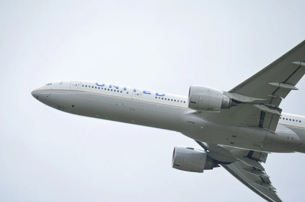 United Airlines Boeing 777 widebody commercial airplane ascending into an overcast sky during takeoff