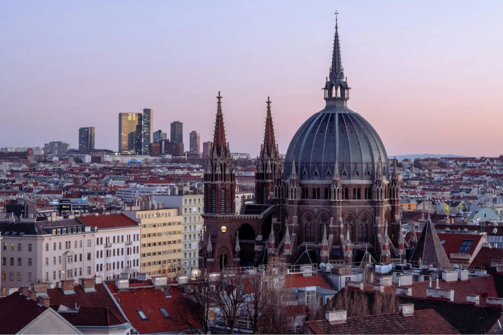 Antonskirche church dome and Vienna skyline with modern skyscrapers at dusk