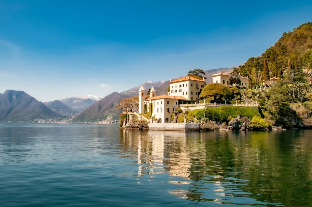 Villa del Balbianello sitting on the edge of Lake Como with mountains in the background